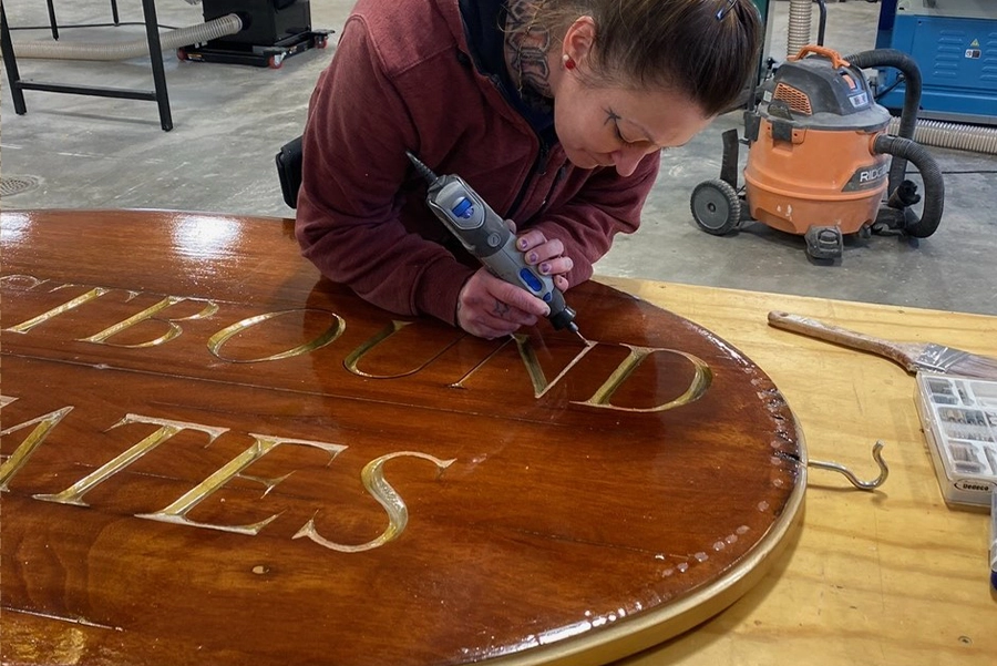 carpenter cutting a wooden pole on a table saw
